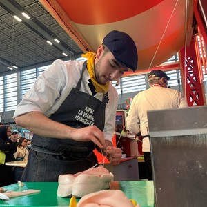 Charlie, appliqué, en plein exercice de ficelage d'un morceau de veau pendant le concours. Charlie en plein exercice de ficelage d'un morceau de veau pendant le concours.