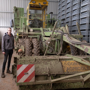 Thibault posant à côté de son "arracheuse". Cette machine est utilisée pour récolter les racines d’endives dans son champ. Agriculteur avec sa machine