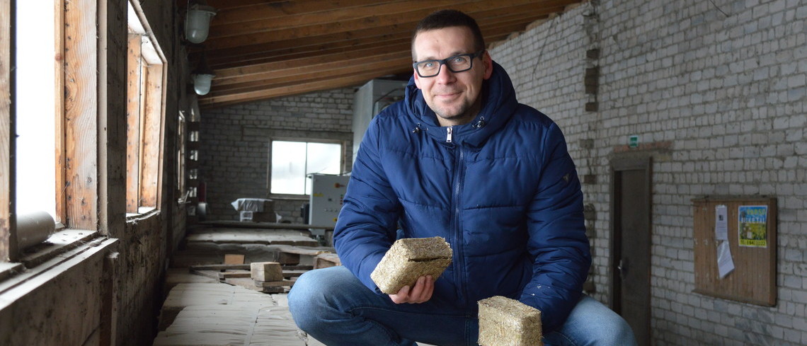 Portrait de Mikas Pačekajus tenant une briquette en paille de colza.