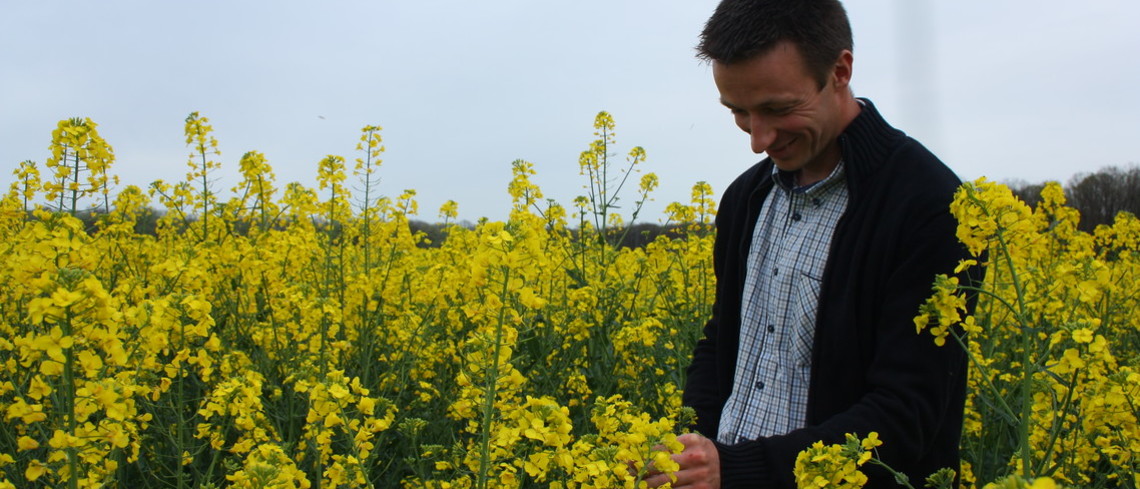 jeune agriculture souriant dans son champ de colza