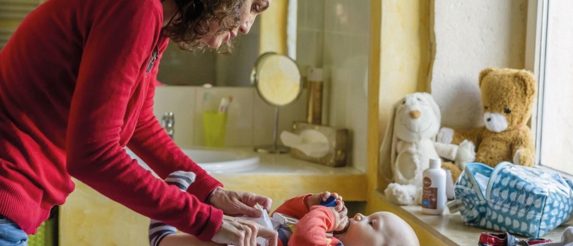 Une femme en train de changer un bébé.