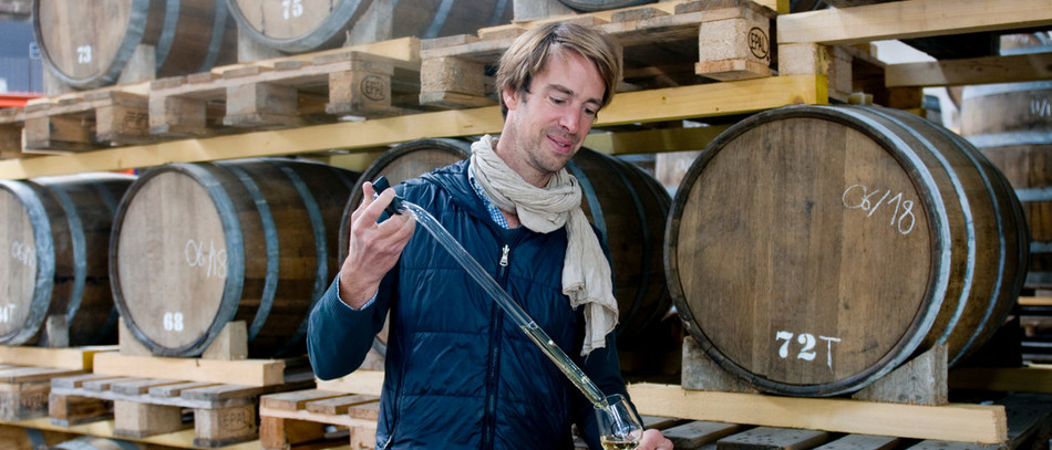 Etienne d'Hautefeuille verse dans un verre du whisky tiré d'un tonneau.