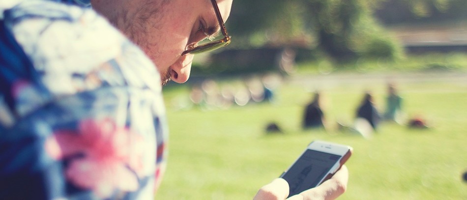 Jeune homme regardant son téléphone portable, dans un parc.