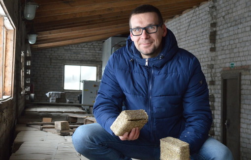 Portrait de Mikas Pačekajus tenant une briquette en paille de colza.