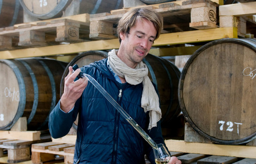 Etienne d'Hautefeuille verse dans un verre du whisky tiré d'un tonneau.