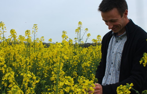 jeune agriculture souriant dans son champ de colza