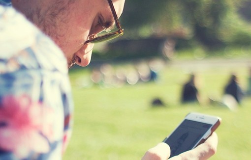 Jeune homme regardant son téléphone portable, dans un parc.